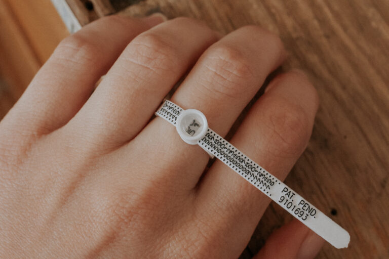 een hand waarop aan één vinger de ringsizer wordt gebruikt om te demonstreren hoe je je ringmaat op kan meten