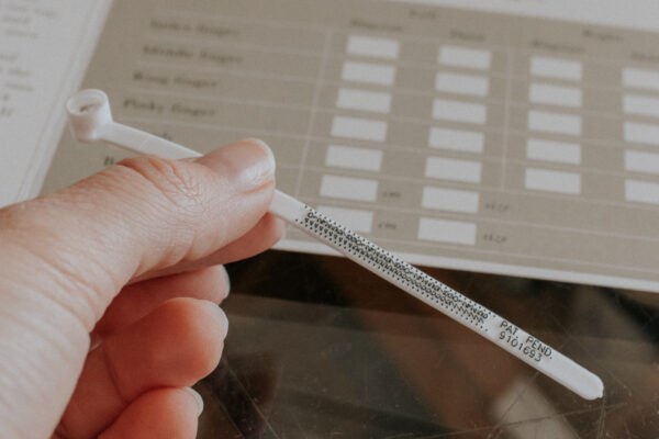 iemanad houdt de ringsizer vast en de ringsize guide ligt op de achtergrond