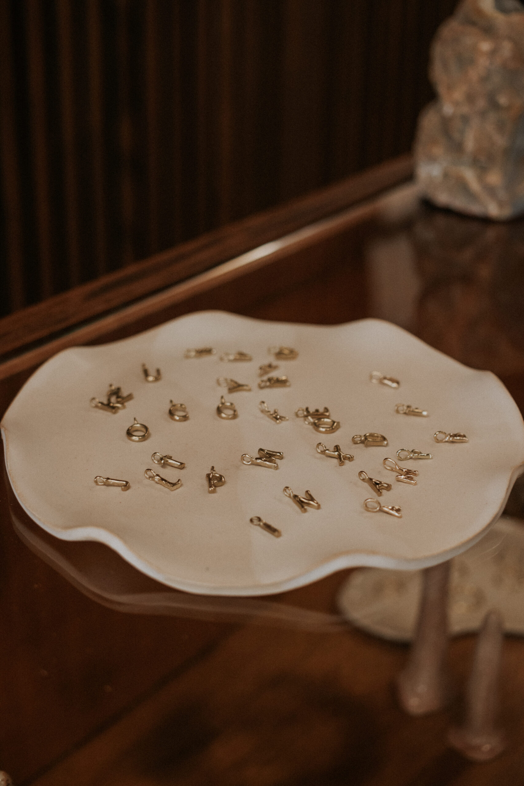 gold alphabet necklace charms displayed on a plate